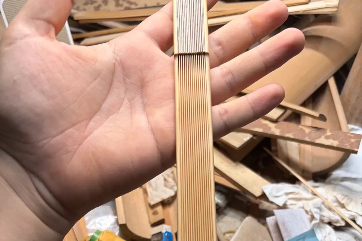 Close-up of a folded fan frame with closely aligned natural-colored ribs.