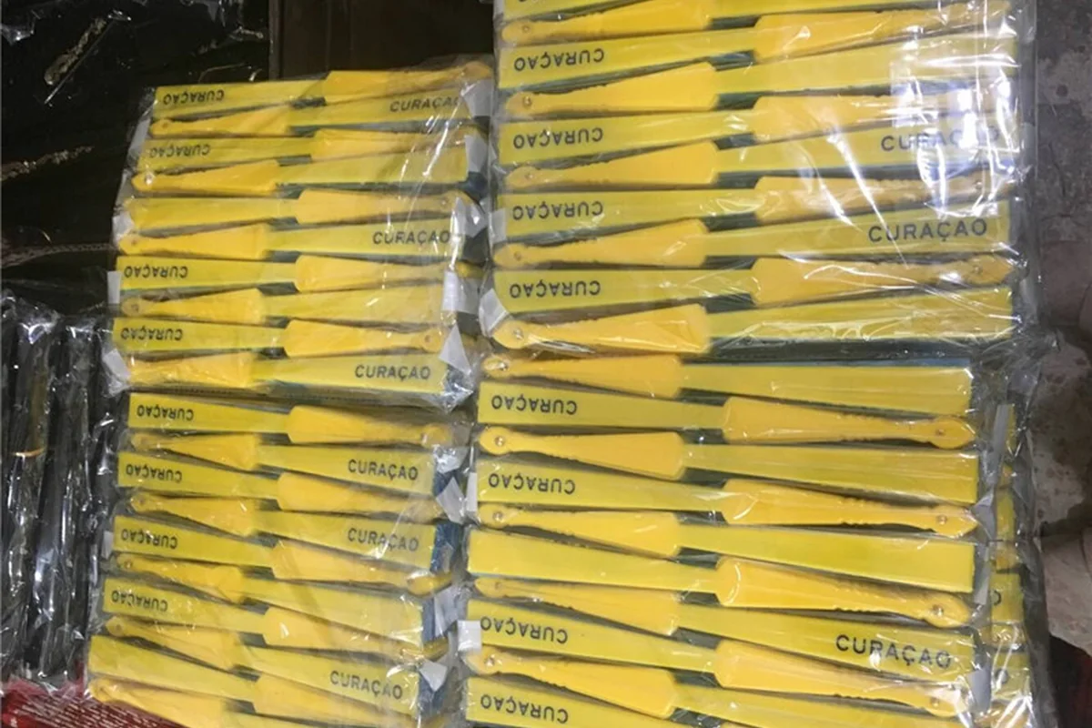 Yellow folding fans individually wrapped and arranged in a bulk group.