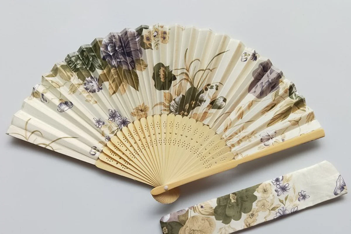 Cream floral folding fan with a matching floral sleeve.