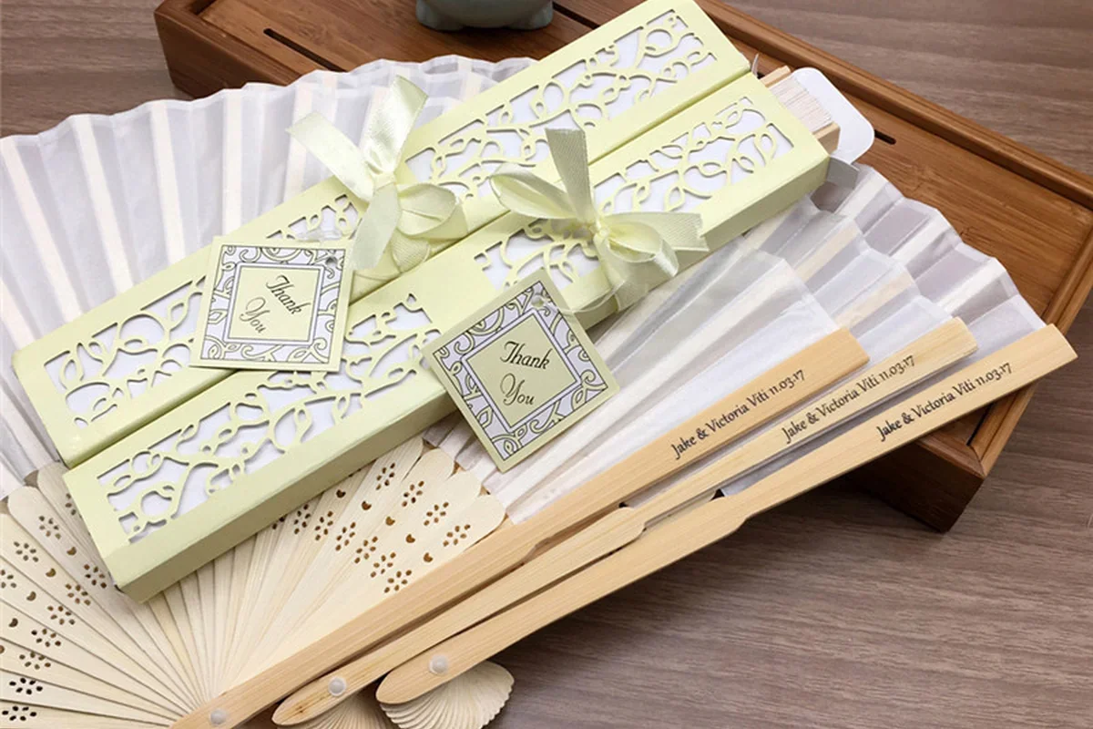 White folding fans beside ribbon-tied decorative gift boxes.