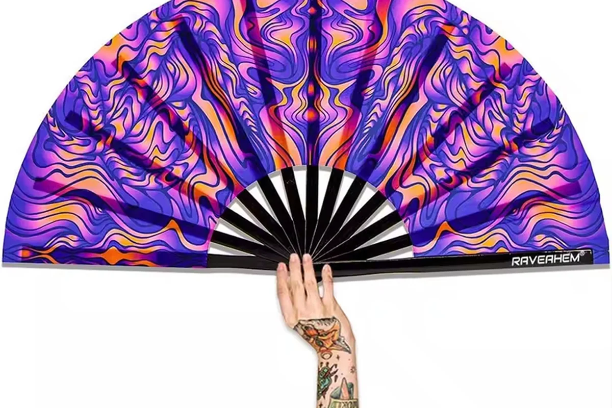 Purple and yellow patterned folding fan held open in one hand.