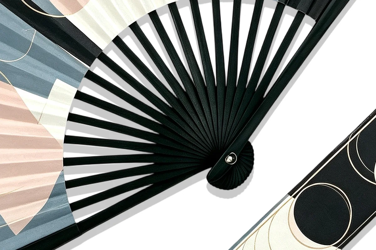 Close-up of black fan ribs and a pivot beneath a geometric print.