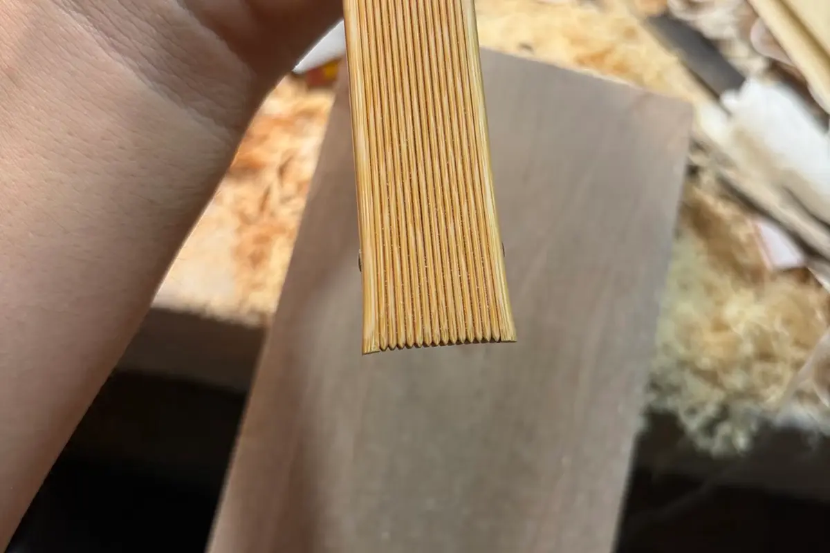 Close-up of aligned fan rib tips held above a workbench.