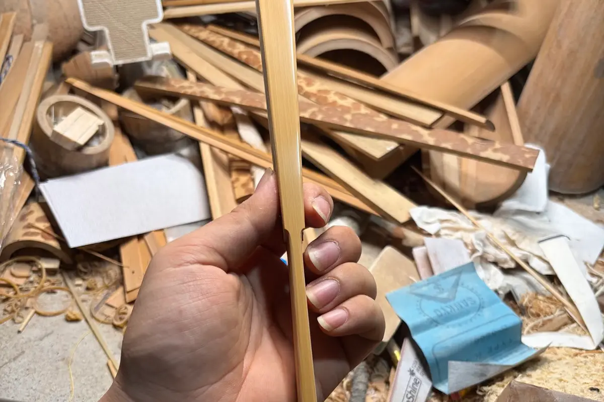 A hand holding a natural-colored fan guard above a workbench.
