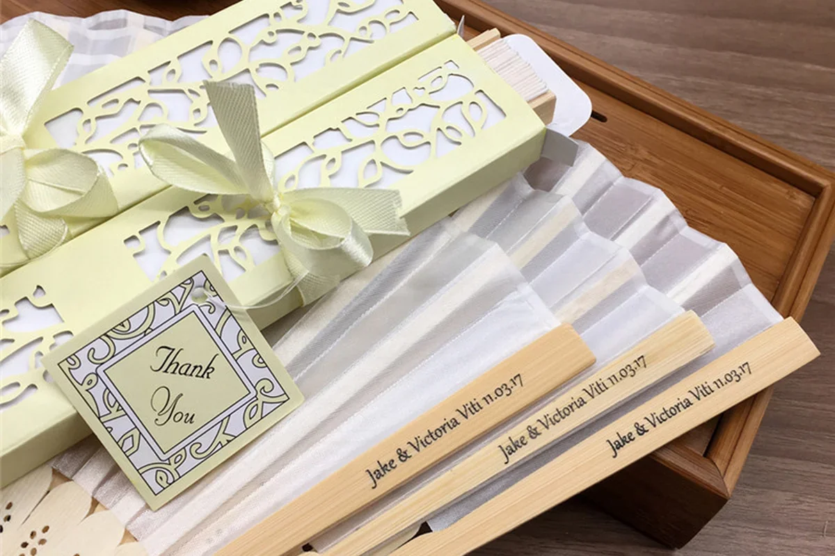 White folding fans beside patterned gift boxes with ribbons and tags.