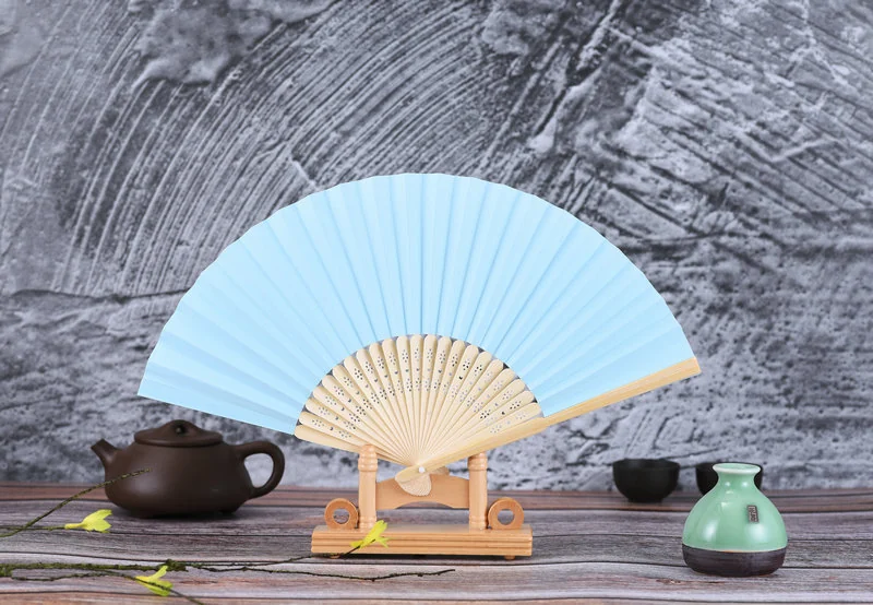 Pale blue blank folding fan displayed on a small stand