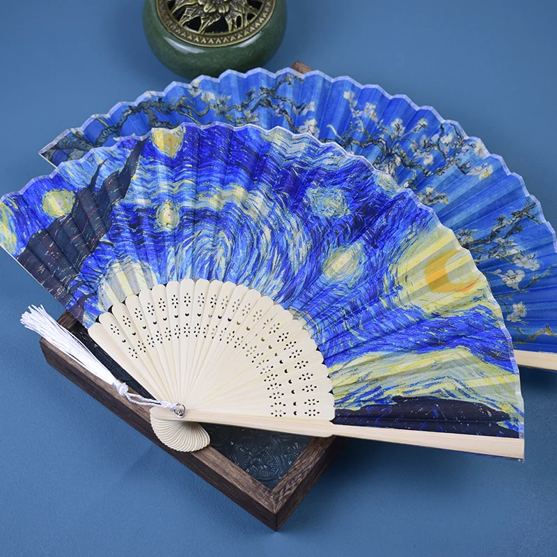 Angled view of several blue art print fans showing the pleats and tassels