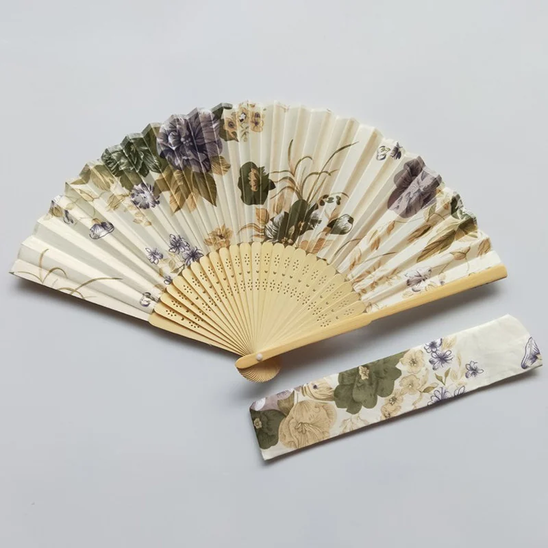 Cream botanical folding fan beside a matching printed sleeve