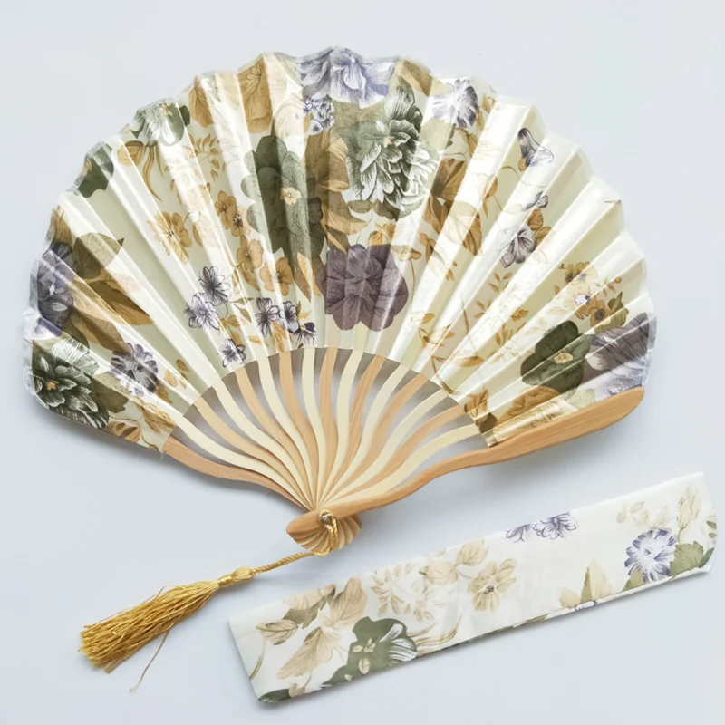 Cream floral fan with curved ribs, a tassel and coordinated sleeve