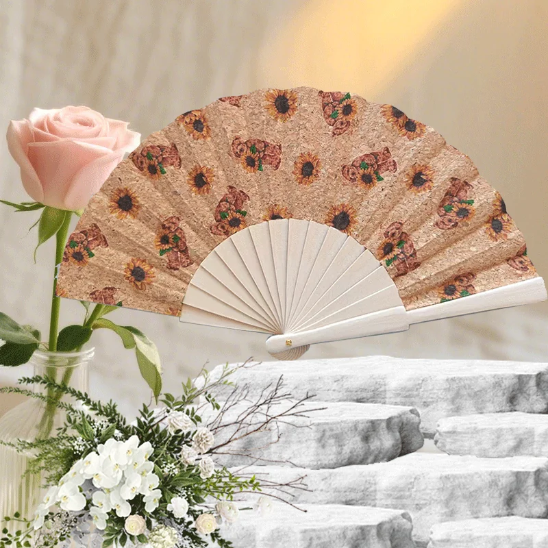 Light tan folding fan with repeated floral motifs in a gift display