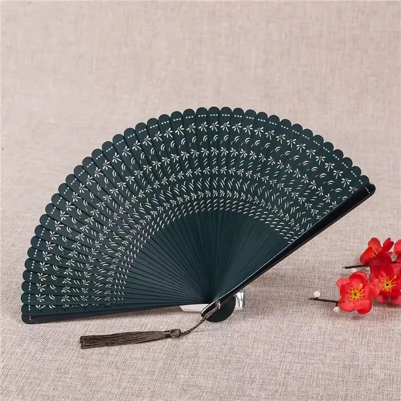 Dark green pierced folding fan displayed with a matching tassel