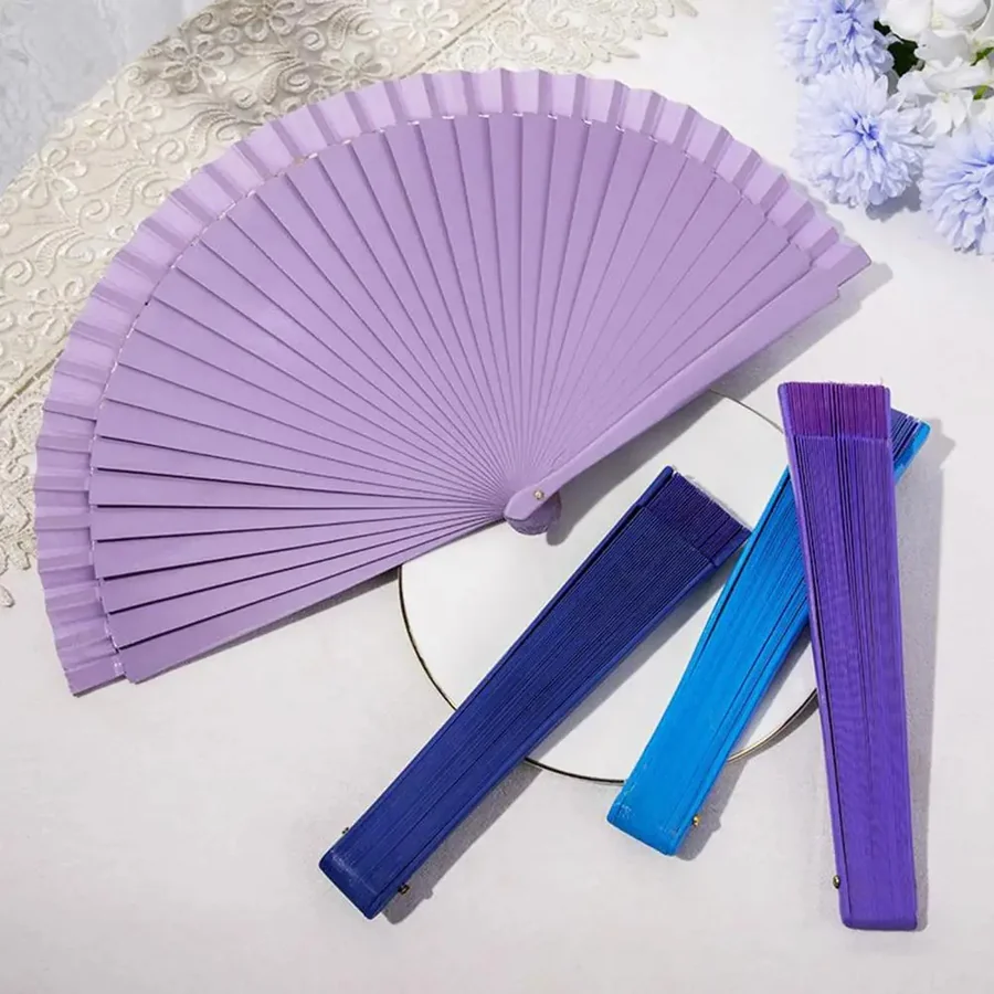 Open lilac folding fan beside several closed fans in cool colors