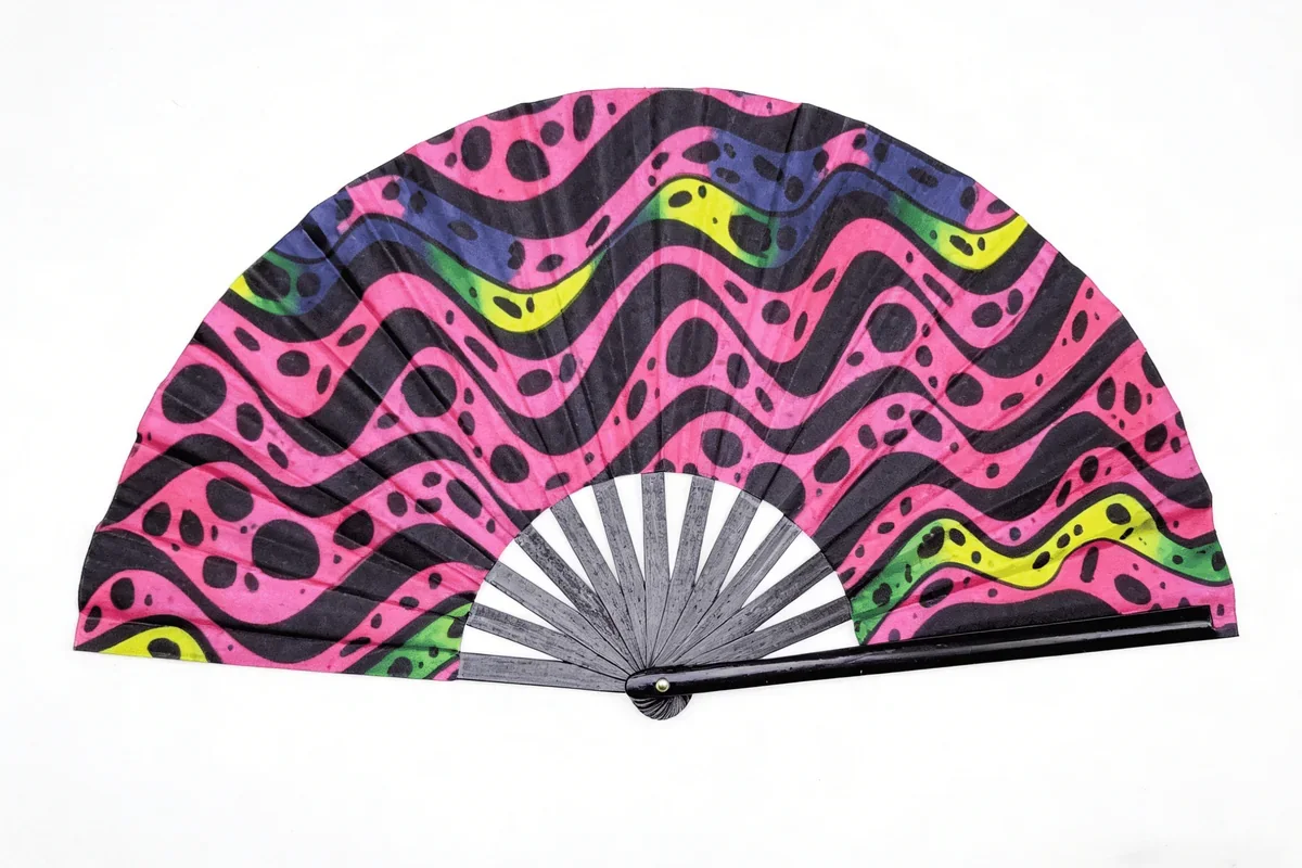 Open folding fan with pink, green and black wave patterns.
